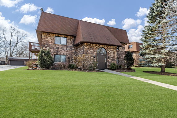 Front view of a two-story brick house with a distinctive sloped roof.
