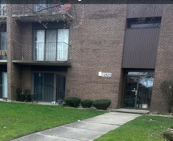 Front view of a multi-story brick building with balconies and main entrance.