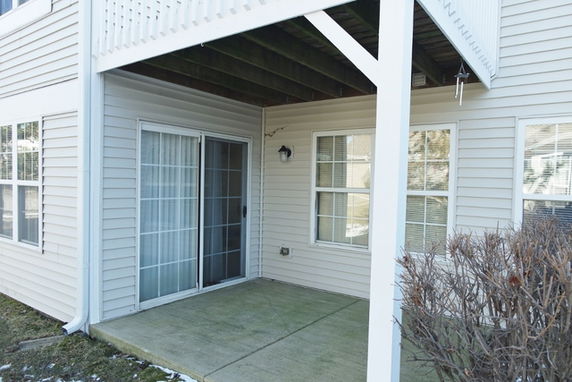 Front view of a building's ground floor with sliding glass doors and covered patio.