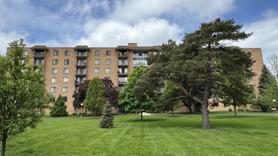 Front view of a multi-story brick apartment building with balconies.