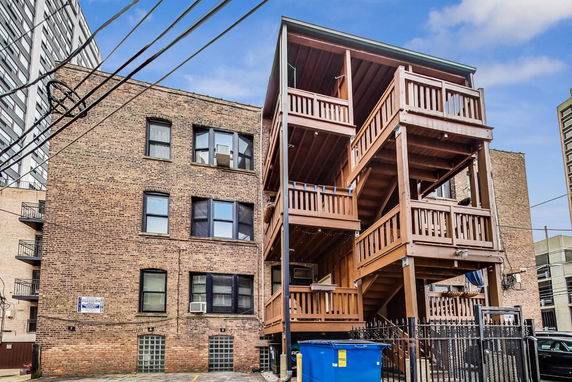 Rear view of a brick multi-story building with wooden balconies.