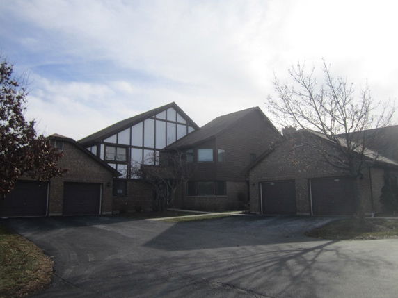 Front view of a modern multi-story house with large glass windows and multiple garage doors.