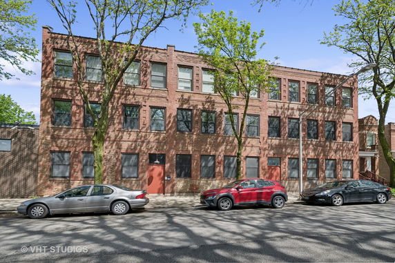 Front view of a three-story brick building with large windows and a flat roof.