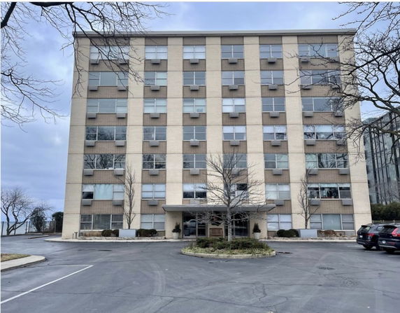 Front view of a multi-story building with parking area in front