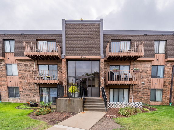 Front view of a three-story apartment building with balconies and brick exterior.