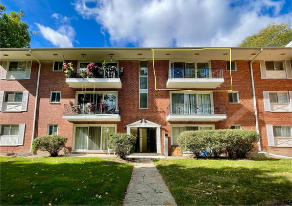 Front view of a multi-story brick apartment building with balconies.