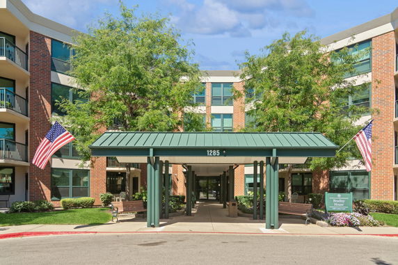 Front view of a multi-story building with a covered entrance and American flags.