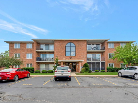 Front view of a three-story brick apartment building with balconies.