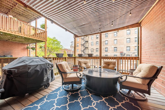 Covered outdoor patio with seating and a barbecue grill.