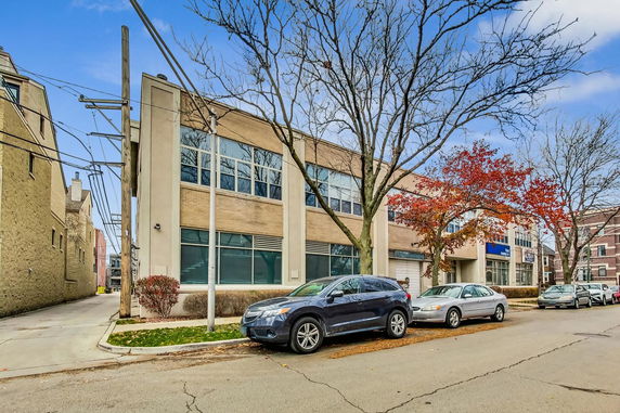 Front view of a two-story commercial building with large windows and street parking.