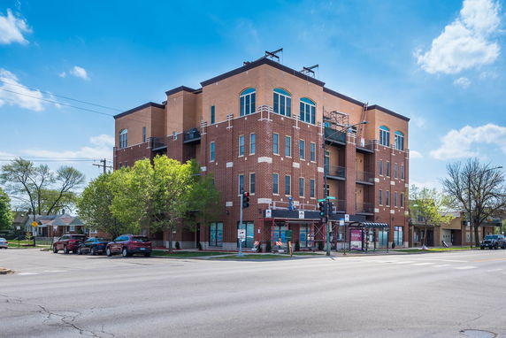 Front view of a multi-story brick building on a street corner.