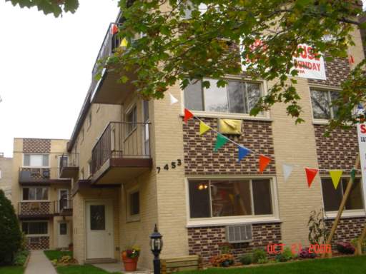 Front view of a multi-story building with balconies and colorful flags.