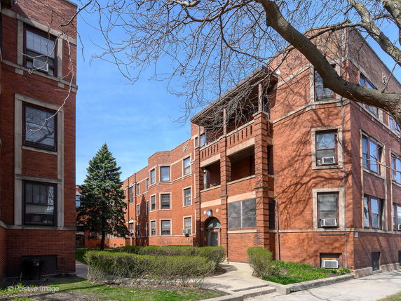 Front view of a multi-story brick building complex with multiple windows and balconies.