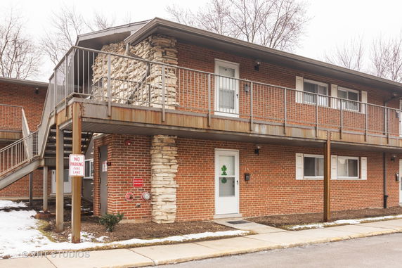 Front view of a two-story brick building with external staircases and railings.