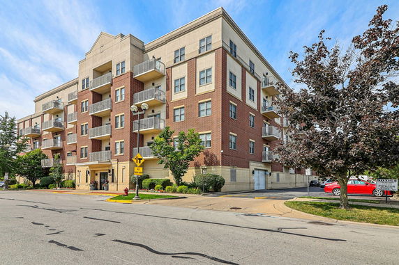 Front view of a multi-story apartment building with balconies and brick facade.