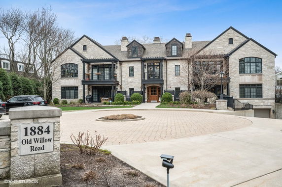 Front view of a large stone residential building with multiple windows and a circular driveway.