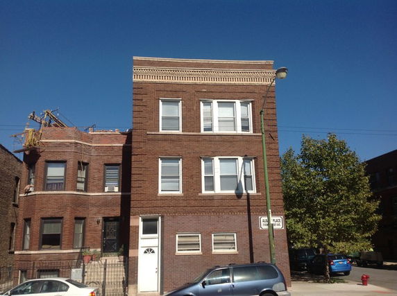 Front view of a multi-story brick building with several windows.