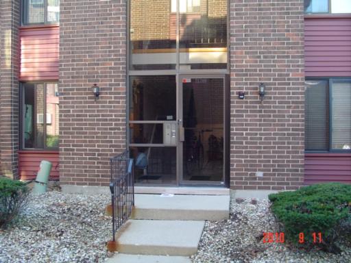 Front view of a brick apartment building entrance with large glass doors.