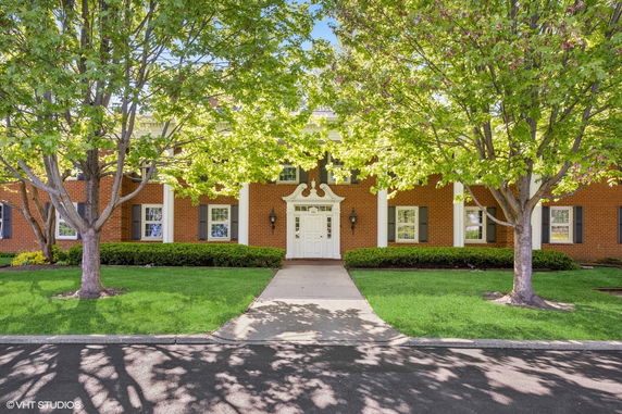 Front view of a two-story brick building with white columns and a decorative entrance.