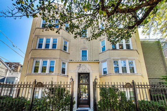 Front view of a multi-story apartment building with a gated entrance.