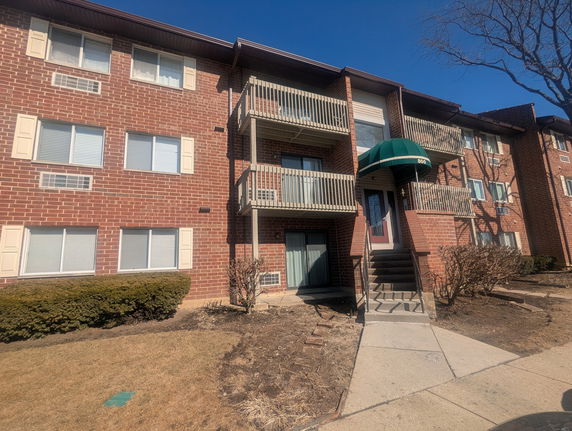 Front view of a brick apartment building with balconies and entrance steps.