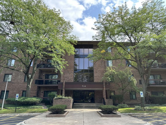 Front view of a multi-story brick building with balconies and large glass windows.