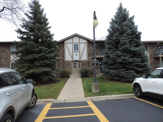 Front view of a two-story apartment building with a gabled roof and brick facade.