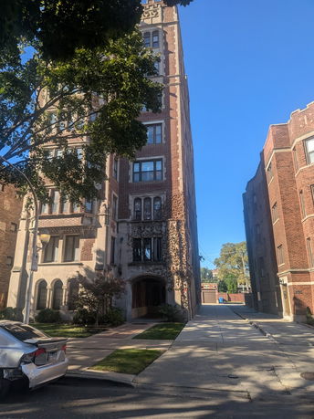Front view of a multi-story building with brick facade and arched entrance.