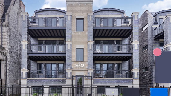 Front view of a multi-story building with multiple balconies and a central entrance.
