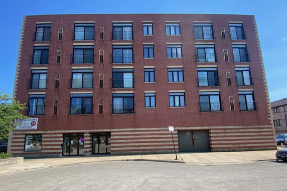 Front view of a multi-story brick building with multiple windows and an entrance.