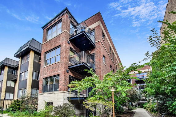 Front view of a multi-story brick apartment building with balconies.