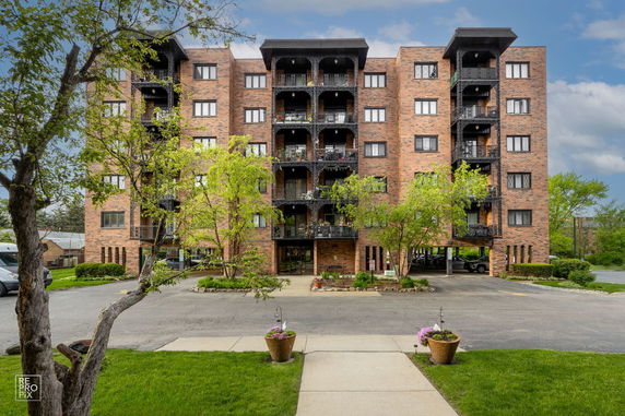 Front view of a multi-story brick apartment building with balconies.