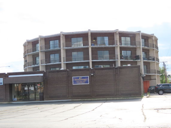 Front view of a multi-story building with balconies and a dermatology office at ground level.