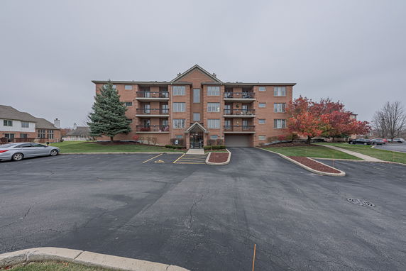 Front view of a multi-story brick apartment building with balconies.