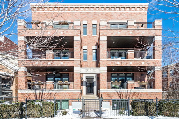 Front view of a three-story brick apartment building with balconies.