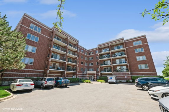 Front view of a multi-story brick apartment building with balconies.