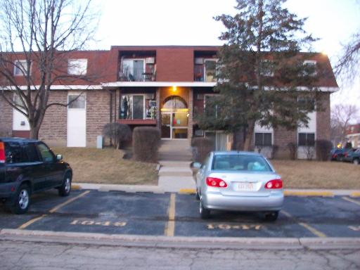 Front view of a multi-story residential building with a parking area in front.