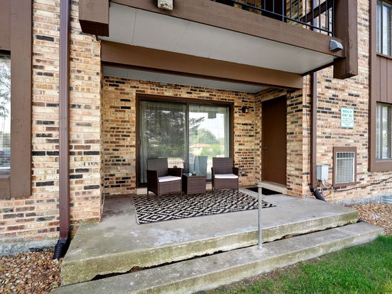 Front view of a brick building with a small porch and outdoor seating.