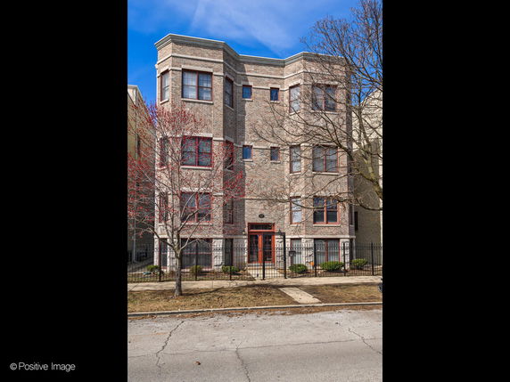 Front view of a multi-story brick building with large windows.