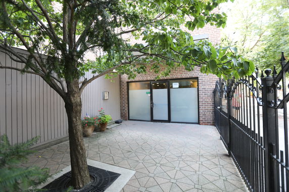 Front view of a building entrance with a tree and metal gate.