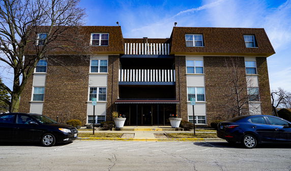 Front view of a multi-story apartment building with a brick facade and large windows.
