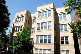 Front view of a multi-story apartment building with large windows.