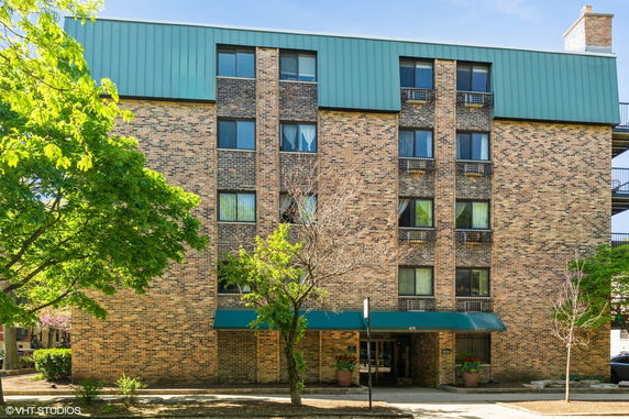 Front view of a multi-story brick building with a teal roof.
