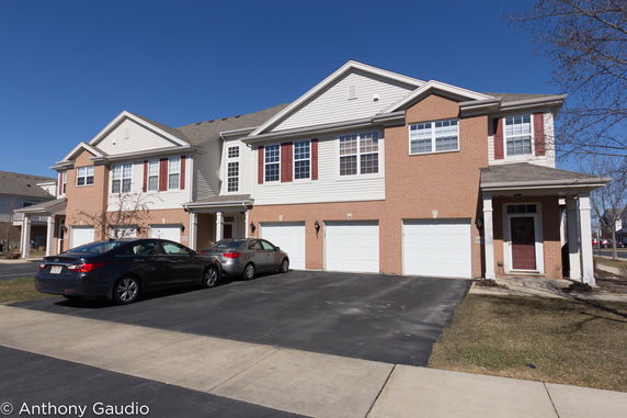 Front view of a two-story townhouse with a garage and driveway.