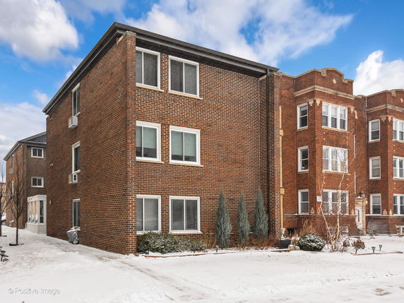 Front view of a brick apartment building in a snowy environment.