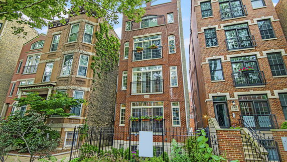 Front view of a multi-story brick building with balconies and large windows.