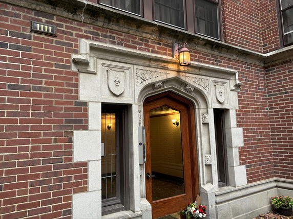 Front view of a building entrance with ornate stone framing and brick exterior walls.