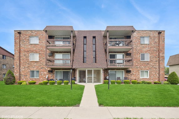 Front view of a three-story apartment building with brick exterior and balconies.