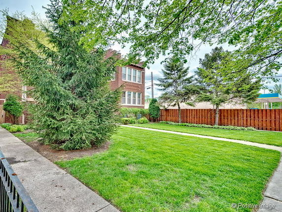Front view of a brick building with surrounding greenery.