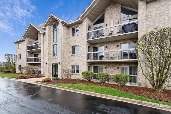 Front view of a multi-story residential building with balconies and brick exterior.